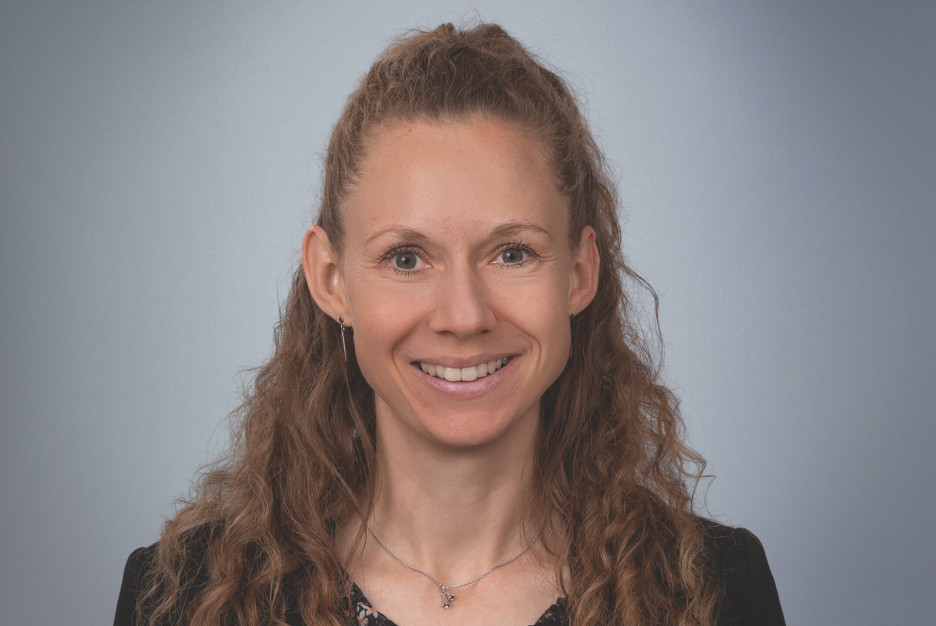 Porträt von Dorothee Marschall mit lächelndem Gesicht auf neutralem Hintergrund.