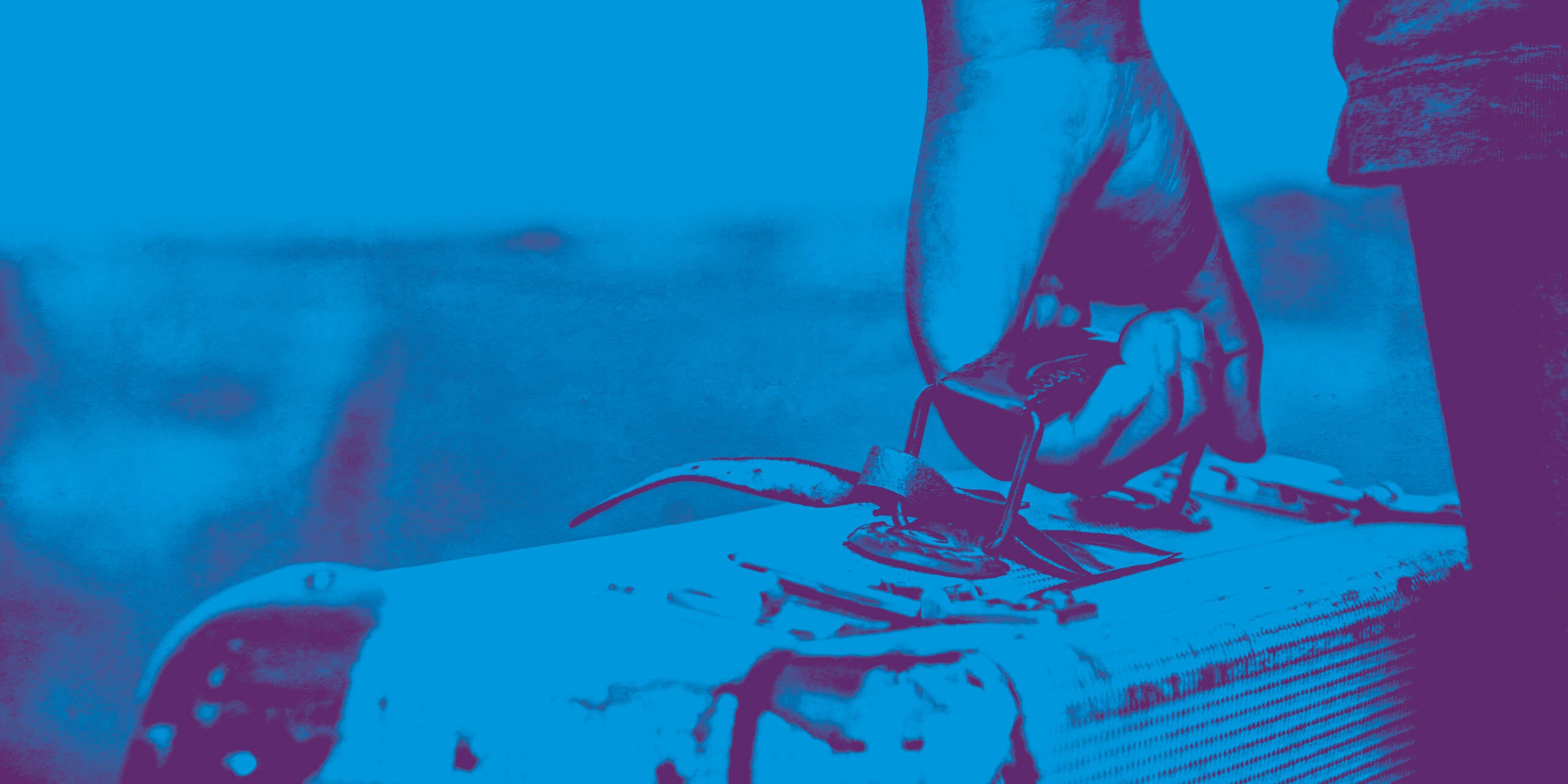 Nahaufnahme einer Hand, die einen alten Koffer hält, in Blau- und Violetttönen gehalten. Die Szene vermittelt das Gefühl von Reise oder Flucht.