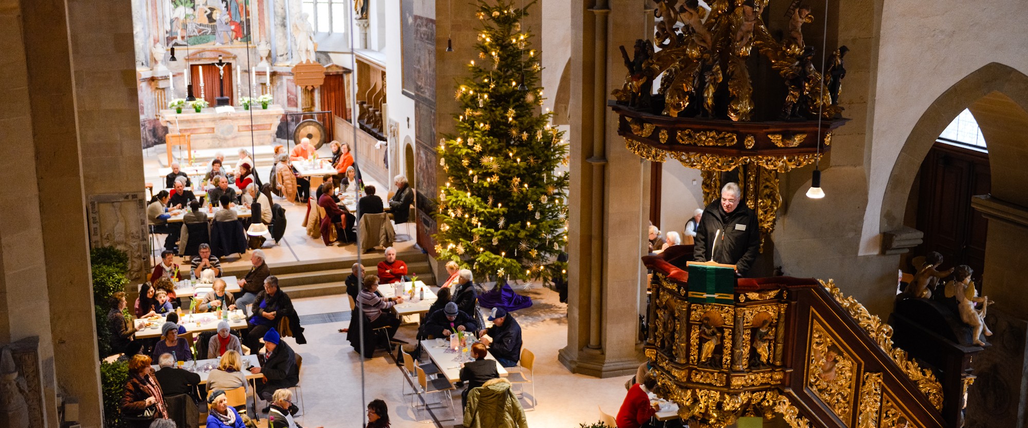 Menschen besuchen die Vesperkirche und sitzen gemeinsam an Tischen.