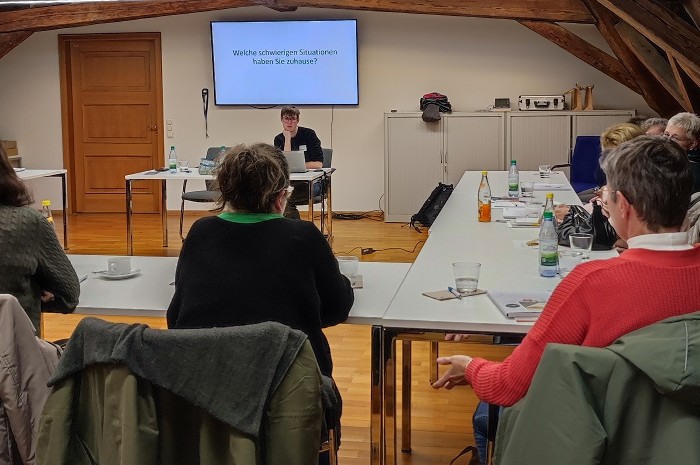 Angehörigenschulung "Hilfe beim Helfen" Personen sitzen an Tischen mit Blick auf eine Präsentation