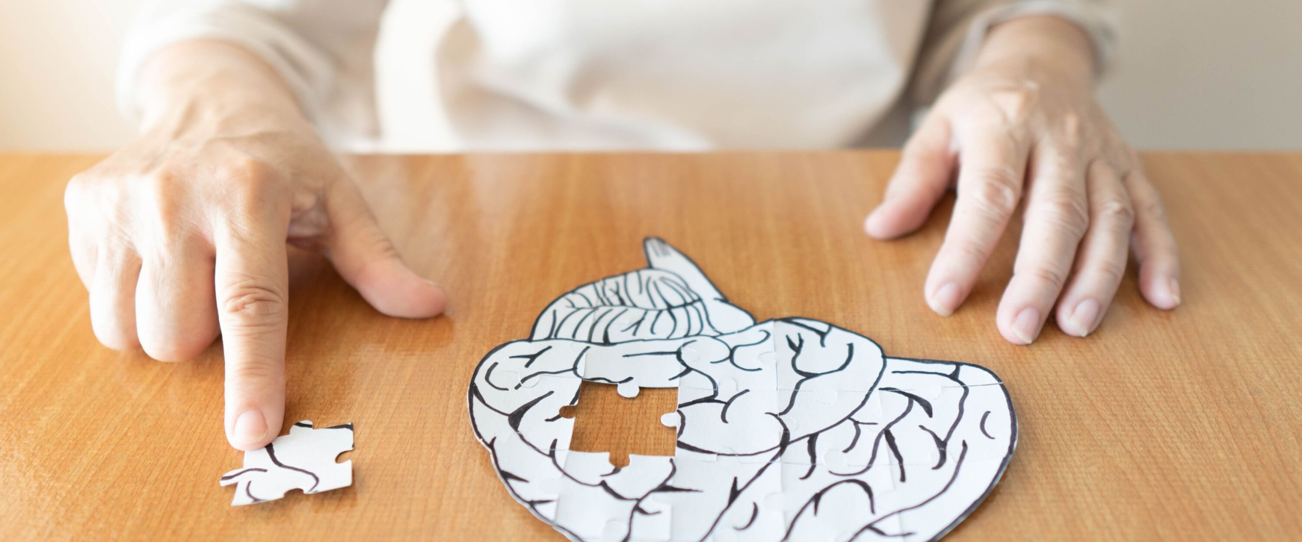 Eine Person fügt das letzte Puzzleteil in ein Gehirn-Puzzle ein, das auf einem Tisch liegt.