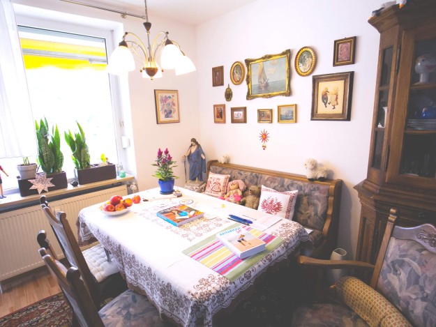 Esszimmer mit Tischdecke, Pflanzen am Fenster und dekorativen Bildern an der Wand.