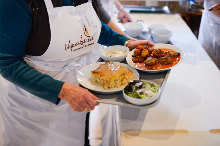 Eine Frau trägt ein Tablett mit Essen bei der Vesperkirche 2023