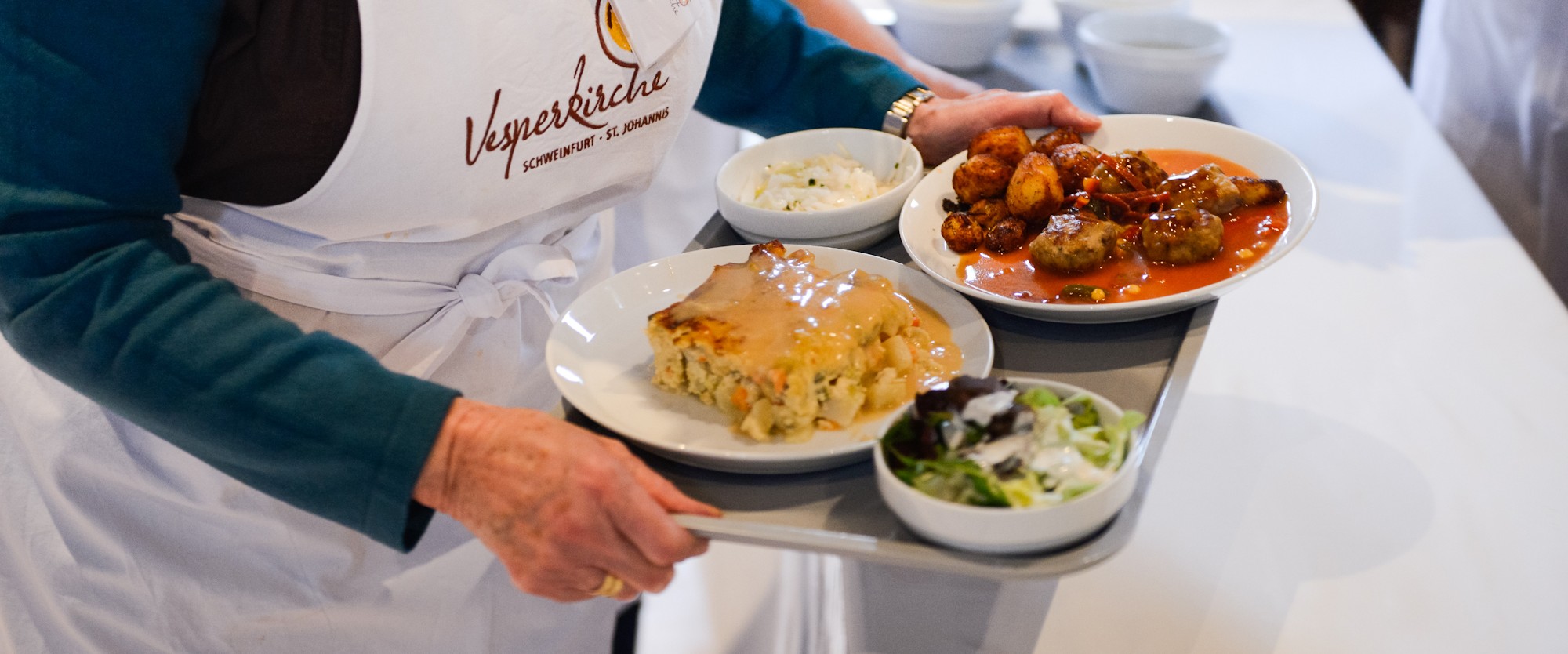 Eine Frau trägt ein Tablett mit Essen bei der Vesperkirche 2023