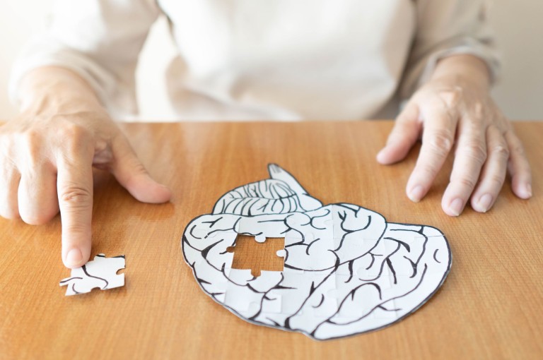 Eine Person fügt das letzte Puzzleteil in ein Gehirn-Puzzle ein, das auf einem Tisch liegt.