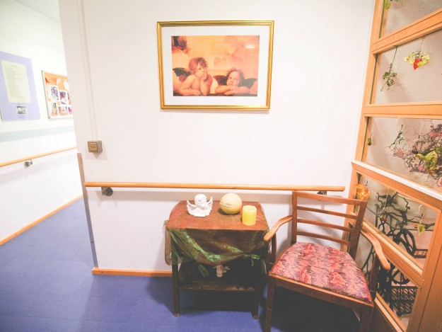 Kleiner Tisch im Flur, geschmückt mit Engelsfigur, Kerze und Bild an der Wand.