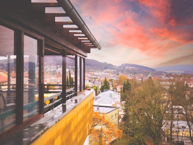 Blick von einer überdachten Terrasse auf die Stadt bei Sonnenuntergang.