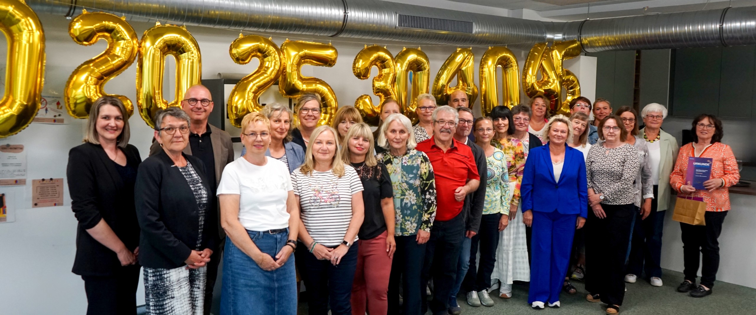 Alle Jubilarinnen und Jubilare stehen nebeneinander vor den Jubiläumszahlen.