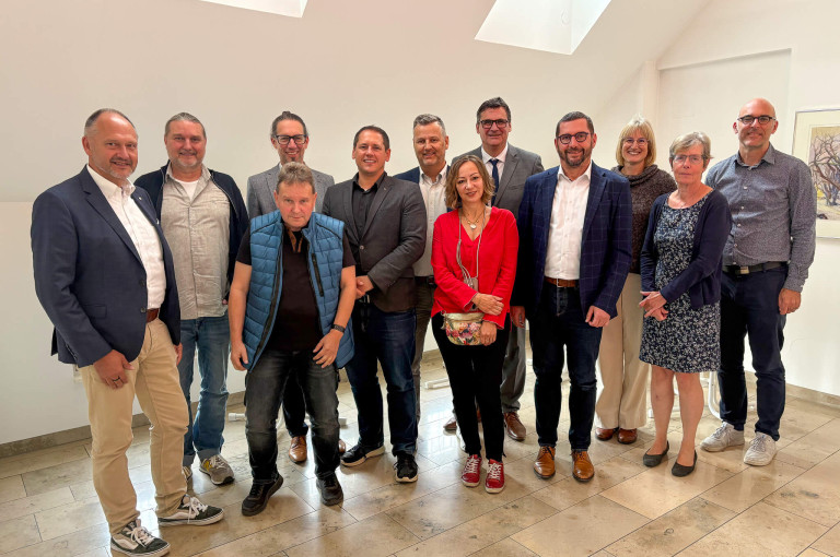 Eine Gruppe von Personen posiert in einem hellen Raum für ein Foto.