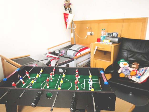 Kleines Bett und Tischkicker in einem Zimmer mit Spielsachen.