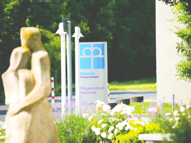 Einfahrt mit Schild und Statue des Pflegezentrums Maininsel