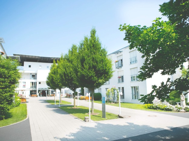 Gepflasterter Eingangsbreich mit Bäumen des Pflegezentrums Maininsel