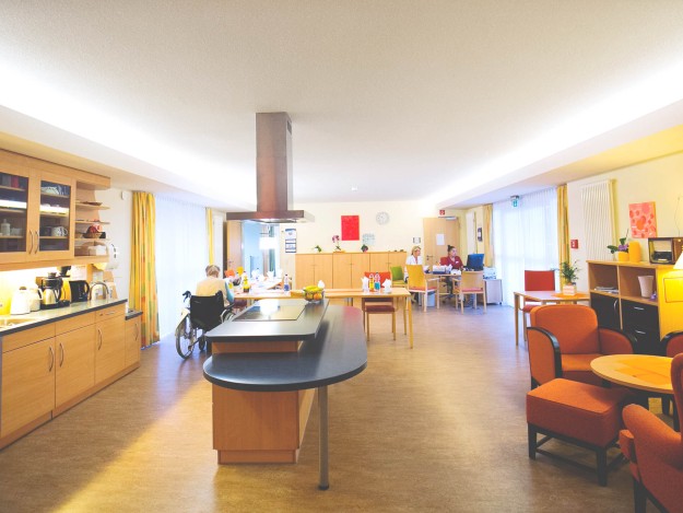 Großzügige Gemeinschaftsküche mit moderner Einrichtung und Sitzgelegenheiten im Seniorenhaus.